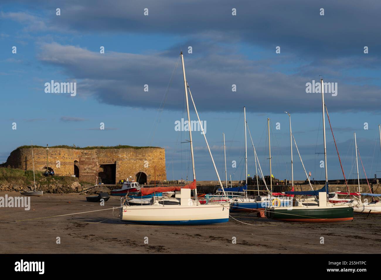 Beadnell, das Fischerdorf an der Küste von Northumberland, ist heute ein beliebter Ferienort und Pendlerort. Segelboote fuhren am Sandstrand an. Alte Kalköfen bey Stockfoto