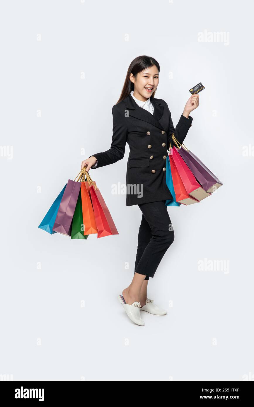 Die schwarz gekleidete Frau ging einkaufen, hatte Kreditkarten und viele Taschen dabei. Stockfoto