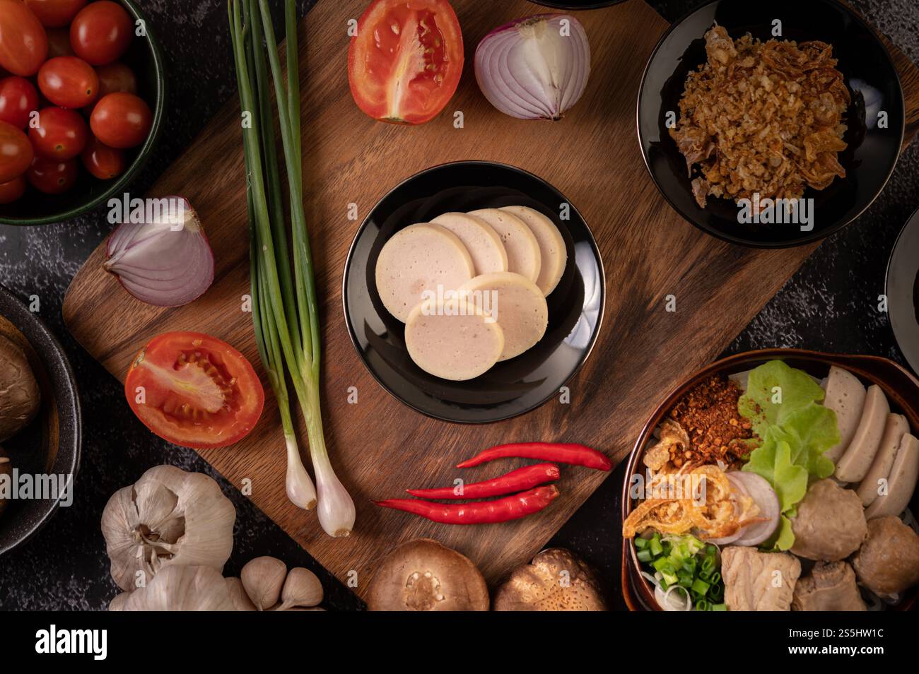 Vietnamesische Wurst auf einem Teller mit Frühlingszwiebeln, Chili, Knoblauch und Shiitake-Pilzen auf einem Holzteller. Stockfoto