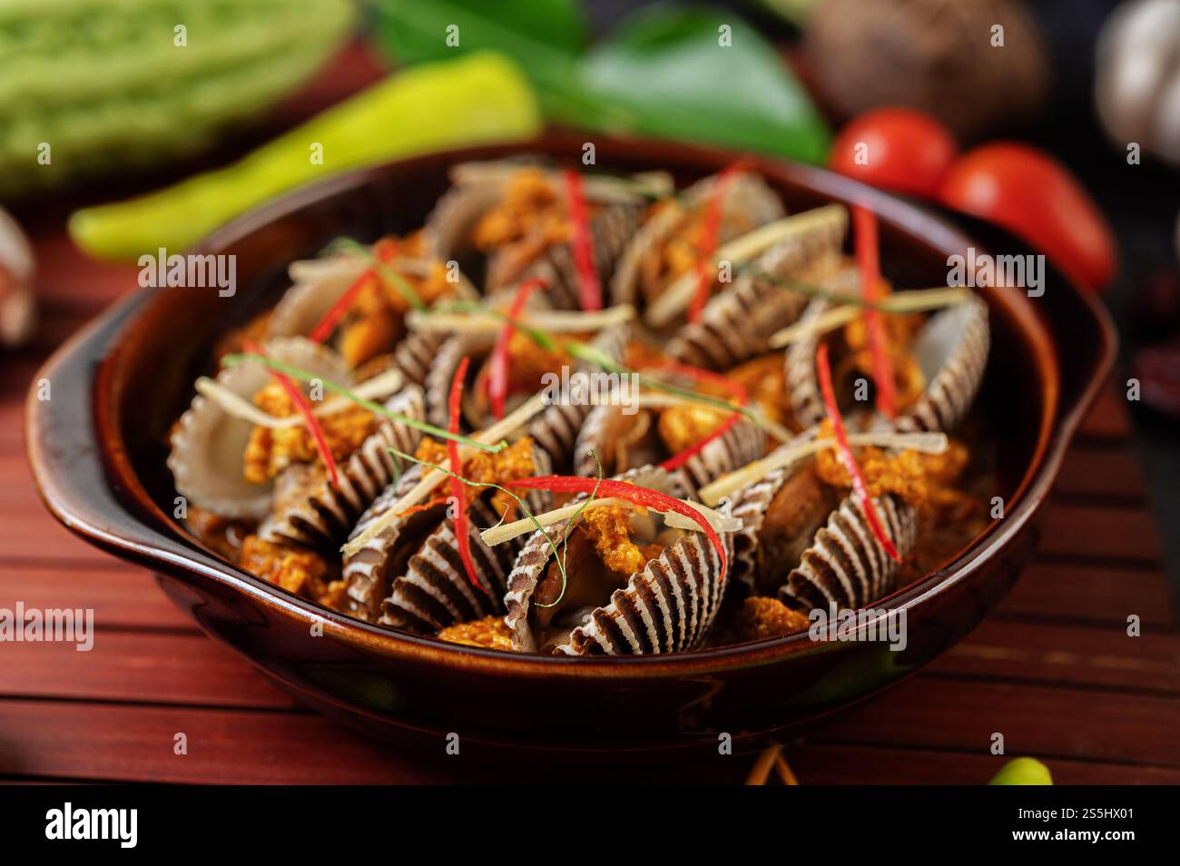 Cockles in Currypulver mit Paprika und Tomaten anbraten. Stockfoto