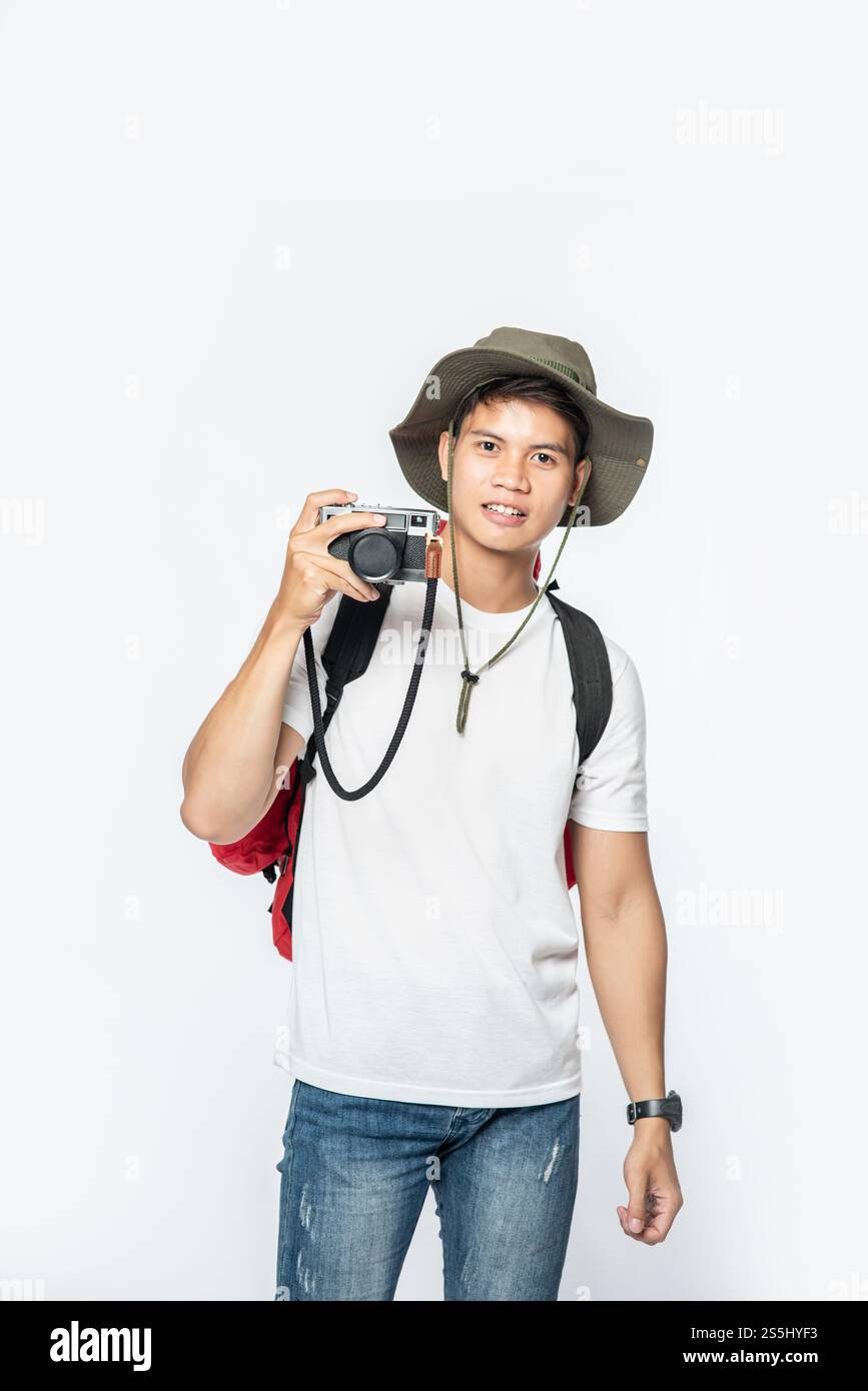 Ein Mann, der mit Hut unterwegs ist und eine Kamera nimmt Stockfoto