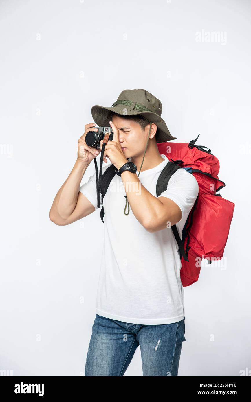 Ein Mann, der mit Hut unterwegs ist und eine Kamera nimmt Stockfoto