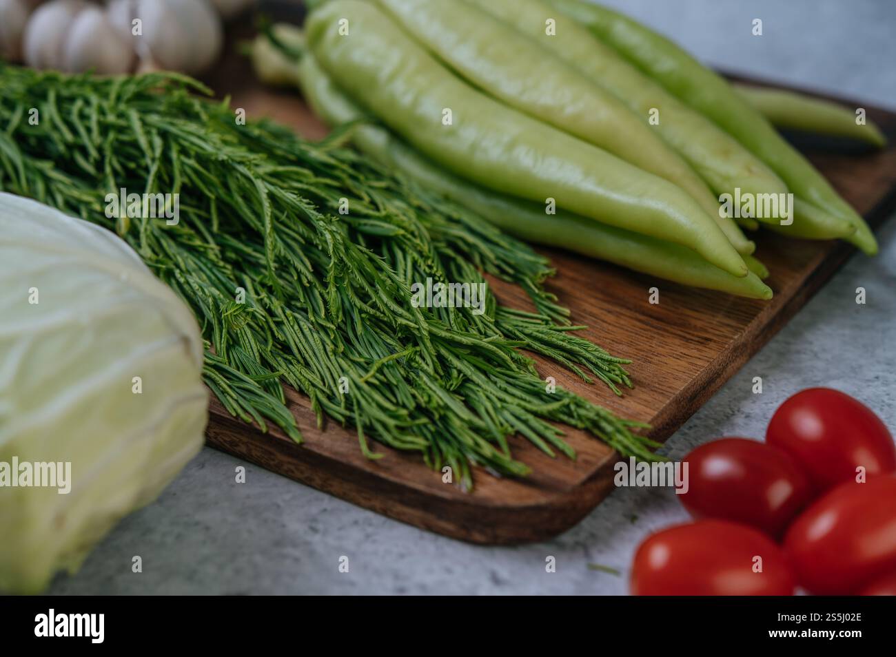 Cha-om, süßer Pfeffer und Knoblauch auf einem hölzernen Schneidebrett. Stockfoto