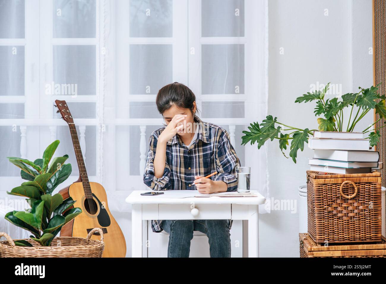 Eine Frau, die an einem Schreibtisch sitzt, analysiert das Dokument und ist gestresst. Stockfoto