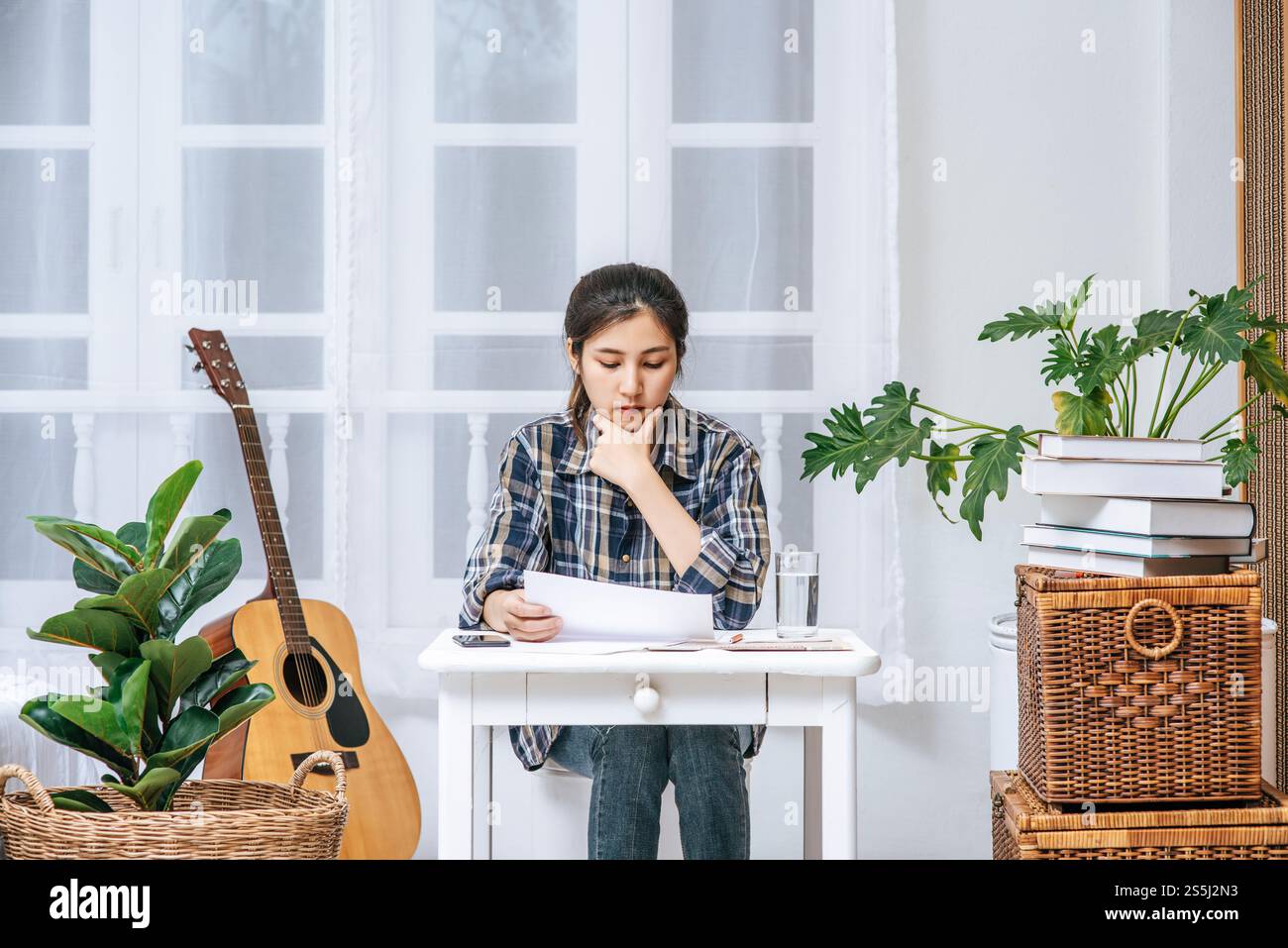 Eine Frau, die an einem Schreibtisch sitzt, analysiert das Dokument und ist gestresst. Stockfoto