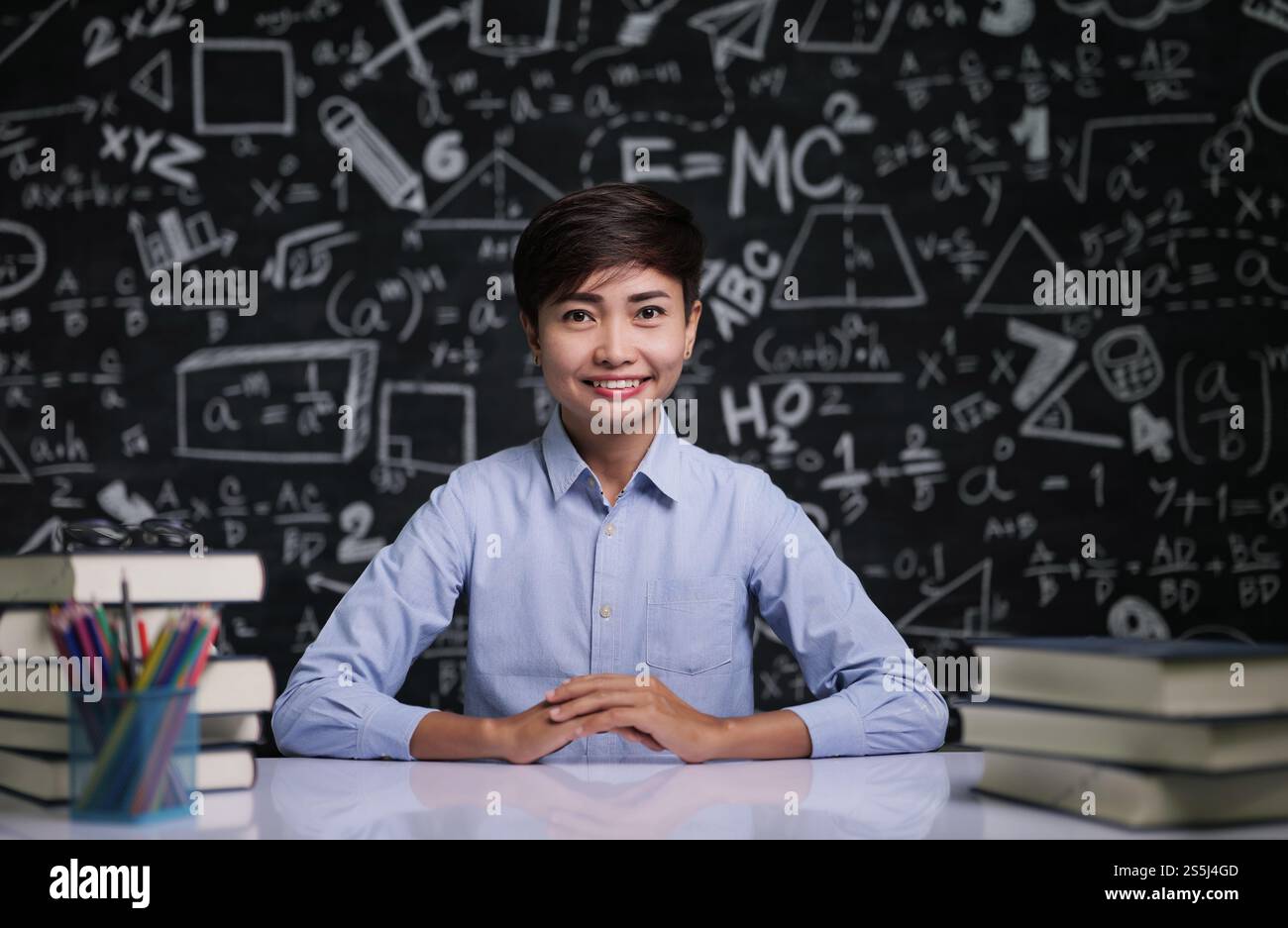 Der Lehrer saß am Tisch, um die Schüler im Klassenzimmer zu unterrichten Stockfoto