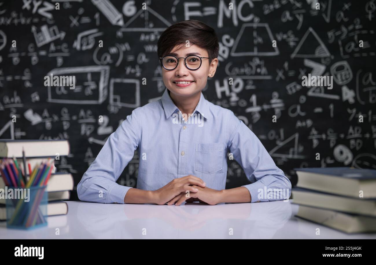 Der Lehrer saß am Tisch, um die Schüler im Klassenzimmer zu unterrichten Stockfoto