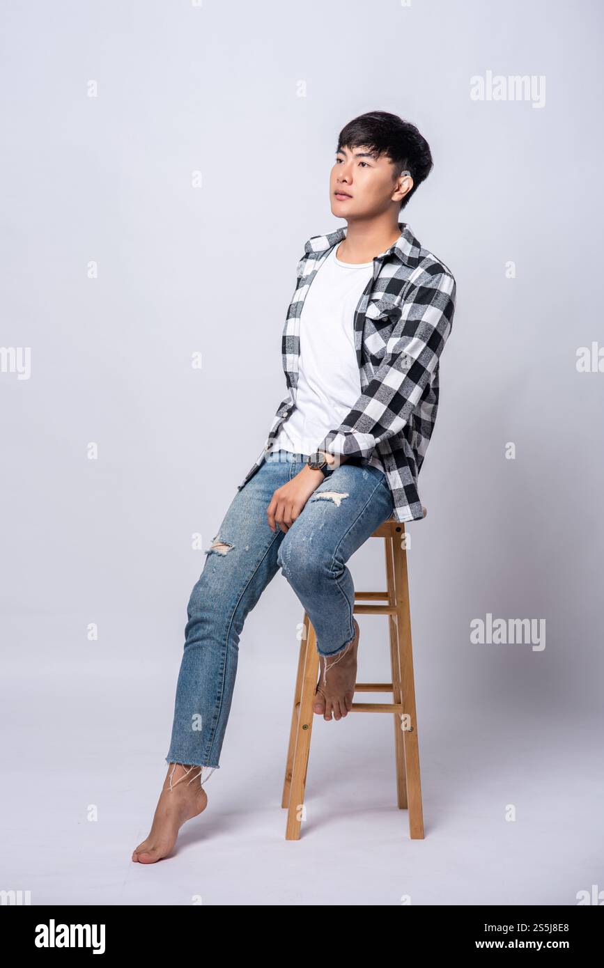 Ein junger Mann in einem gestreiften Hemd sitzt auf einem Hochstuhl. Stockfoto Ein junger Mann in einem gestreiften Hemd sitzt auf einem Hochstuhl. Stockfoto