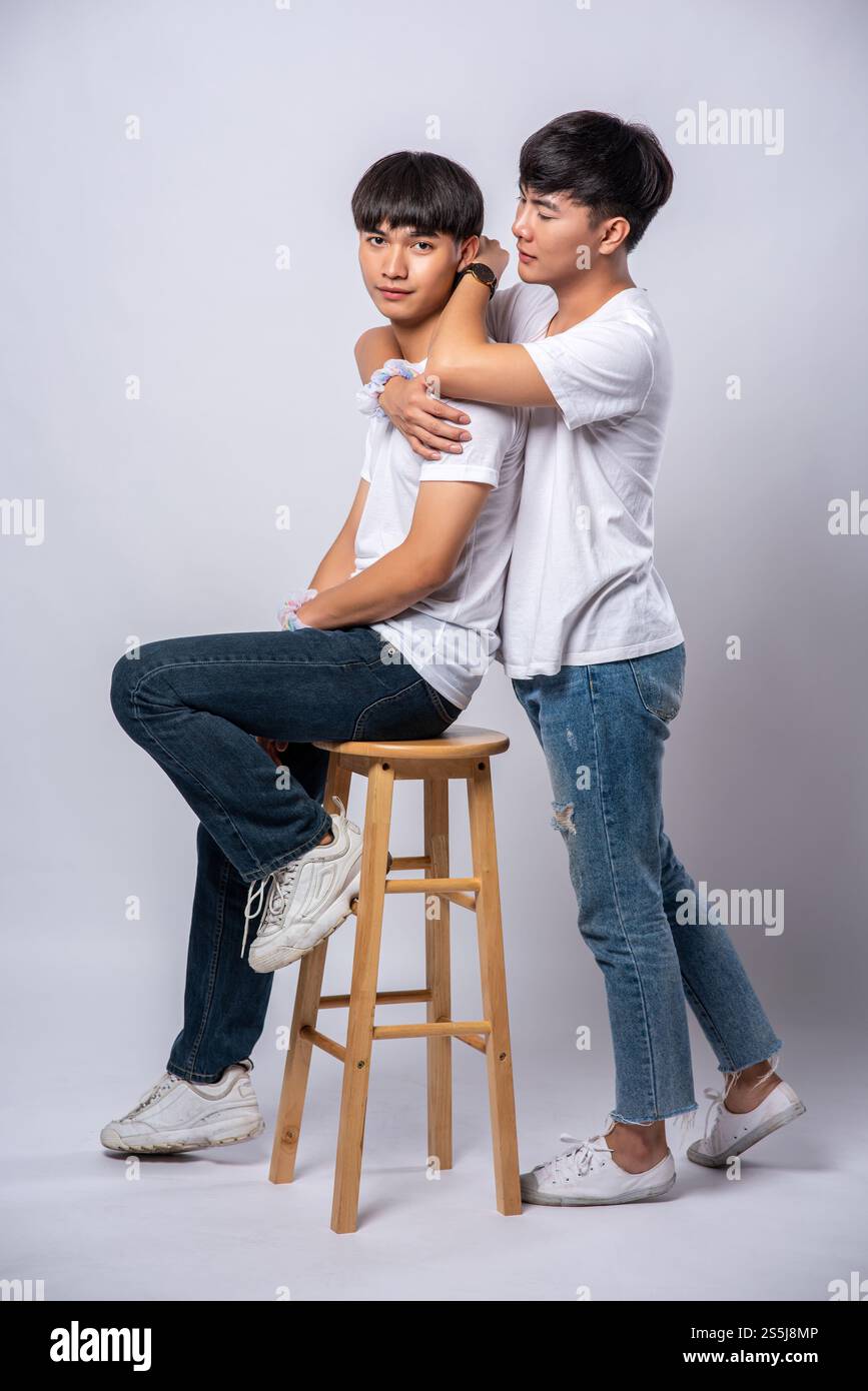 Zwei Männer, die einander lieben, umarmen und sitzen auf einem Stuhl. Stockfoto