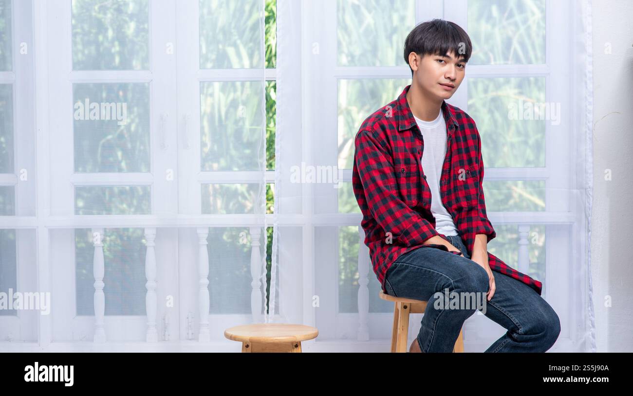Ein junger Mann in einem gestreiften Hemd sitzt auf einem Hochstuhl. Stockfoto Ein junger Mann in einem gestreiften Hemd sitzt auf einem Hochstuhl. Stockfoto