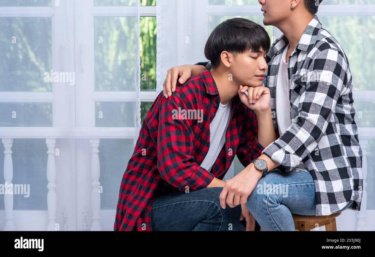 Zwei Männer, die einander lieben, umarmen und sitzen auf einem Stuhl. Stockfoto