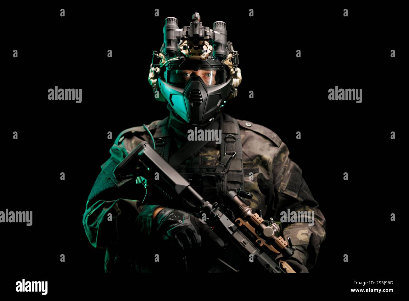 Ein Soldat, der fortschrittliche Militärausrüstung trägt, einschließlich eines taktischen Helms, und eine Schusswaffe in der Hand hält, vor dunklem Hintergrund. Das Bild zeigt Professi Stockfoto
