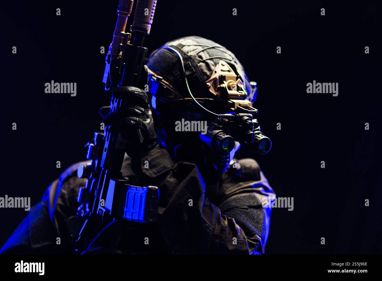 Ein taktischer Soldat, der Nachtsichtgeräte trägt, posiert mit einer Waffe in einer dunklen Umgebung und betont die Bereitschaft und strategische militärische Operation Stockfoto