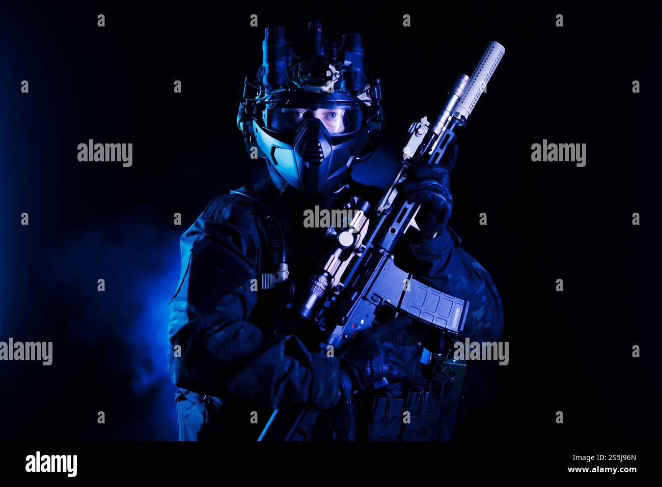 Ein professioneller Soldat, der auf Operationen vorbereitet ist, eine fortschrittliche Schusswaffe und taktische Ausrüstung in einer stimmungsvollen Beleuchtung trägt. Ideal für Conce Stockfoto