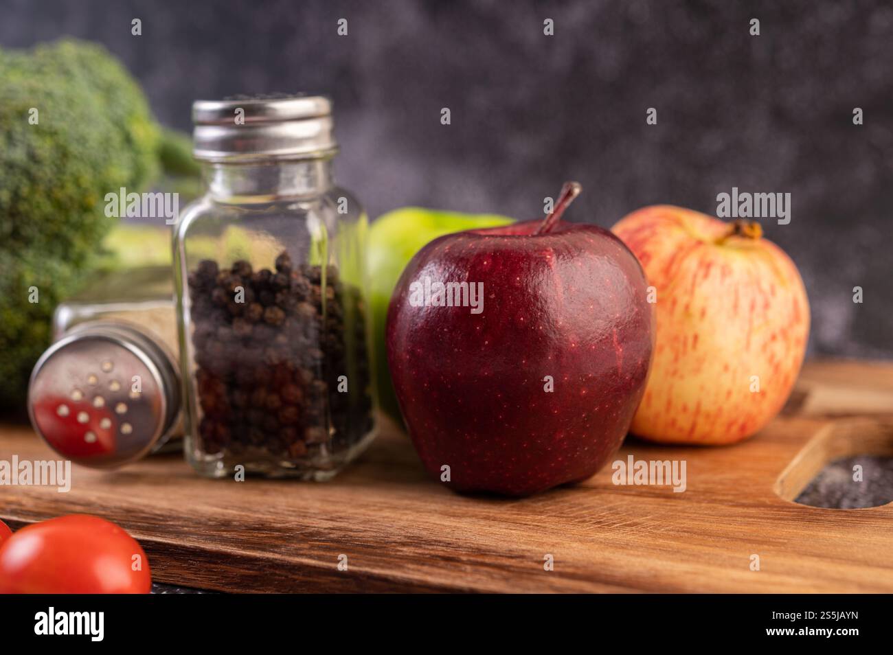 Apfel auf einem Holzbrett mit einem Glas Pfeffersamen Stockfoto