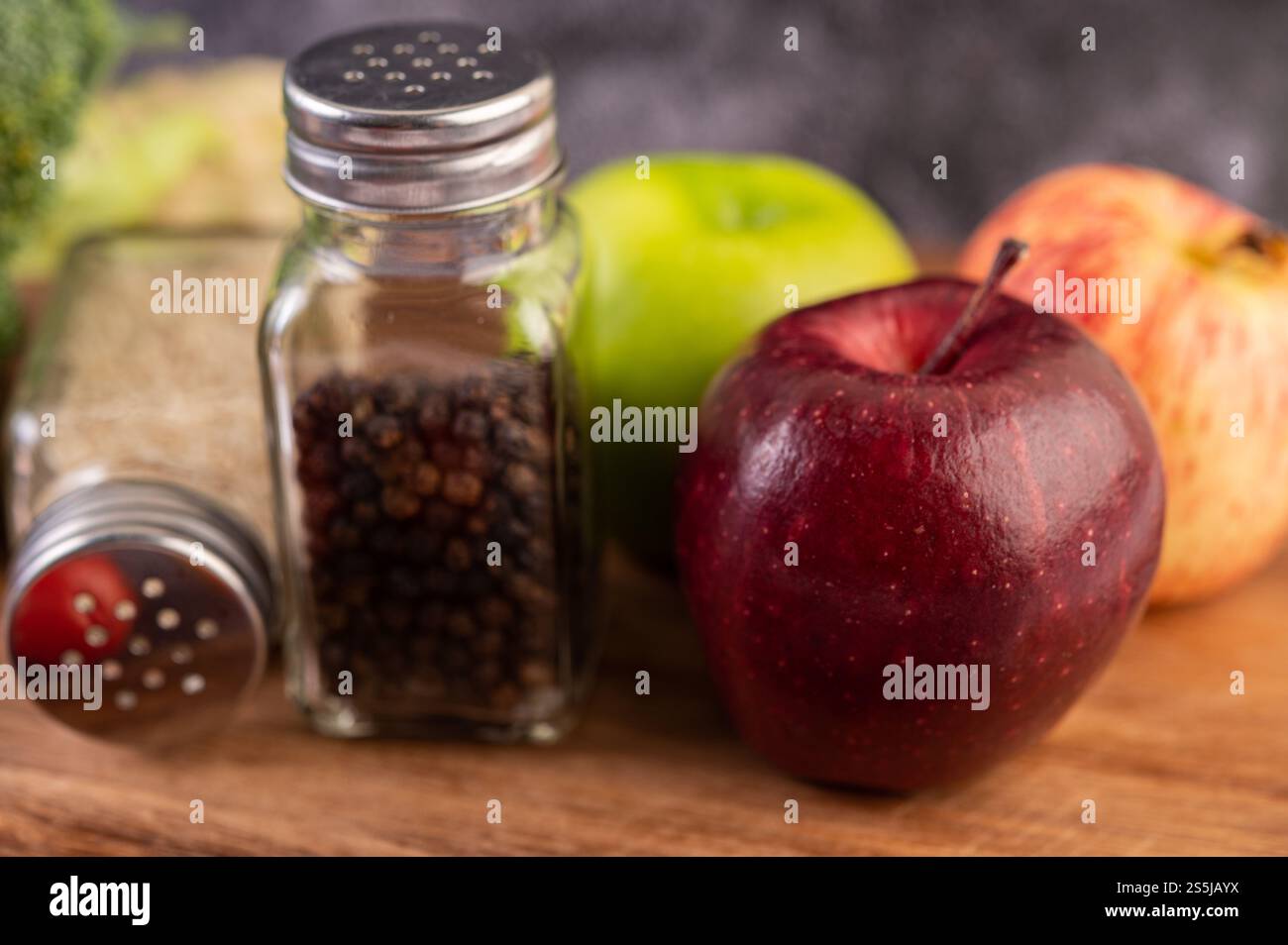 Apfel auf einem Holzbrett mit einem Glas Pfeffersamen Stockfoto