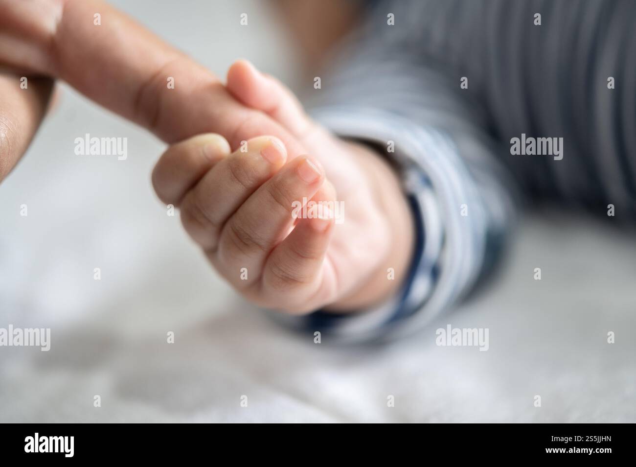 Die Hand des Neugeborenen, die die Finger der Mutter hält Stockfoto