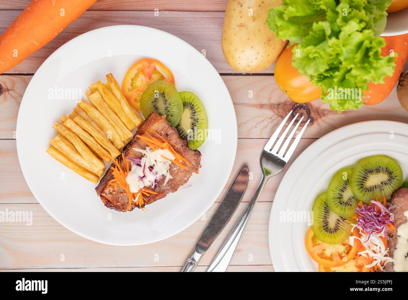 Fischsteak mit Pommes frites, Kiwi, Salat, Karotten, Tomaten, und Kohl in einer weißen Schale Stockfoto