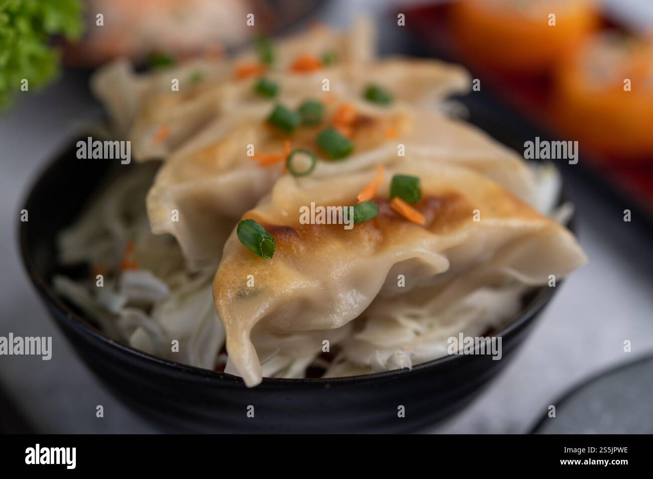 Gyoza in einer schwarzen Tasse mit Sushi. Selektiver Fokus. Stockfoto