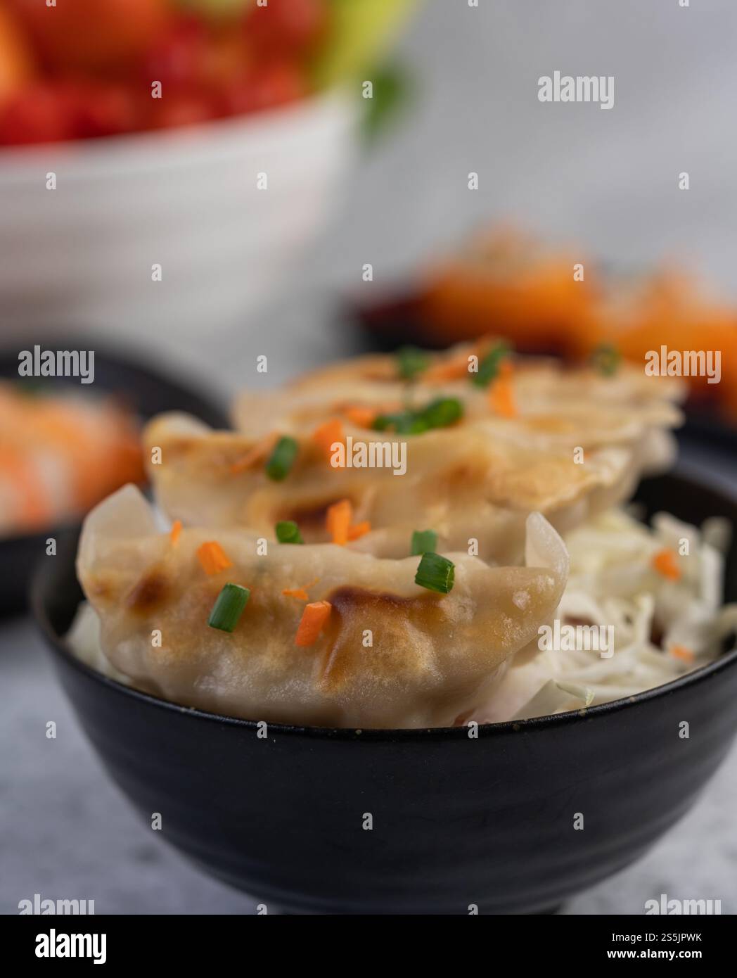 Gyoza in einer schwarzen Tasse mit Sushi. Selektiver Fokus. Stockfoto