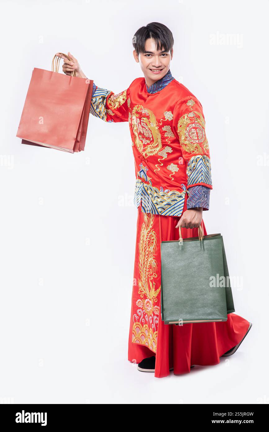 Mann trägt Cheongsam Anzug Lächeln mit Papiertüte vom Einkaufen im chinesischen Neujahr Stockfoto