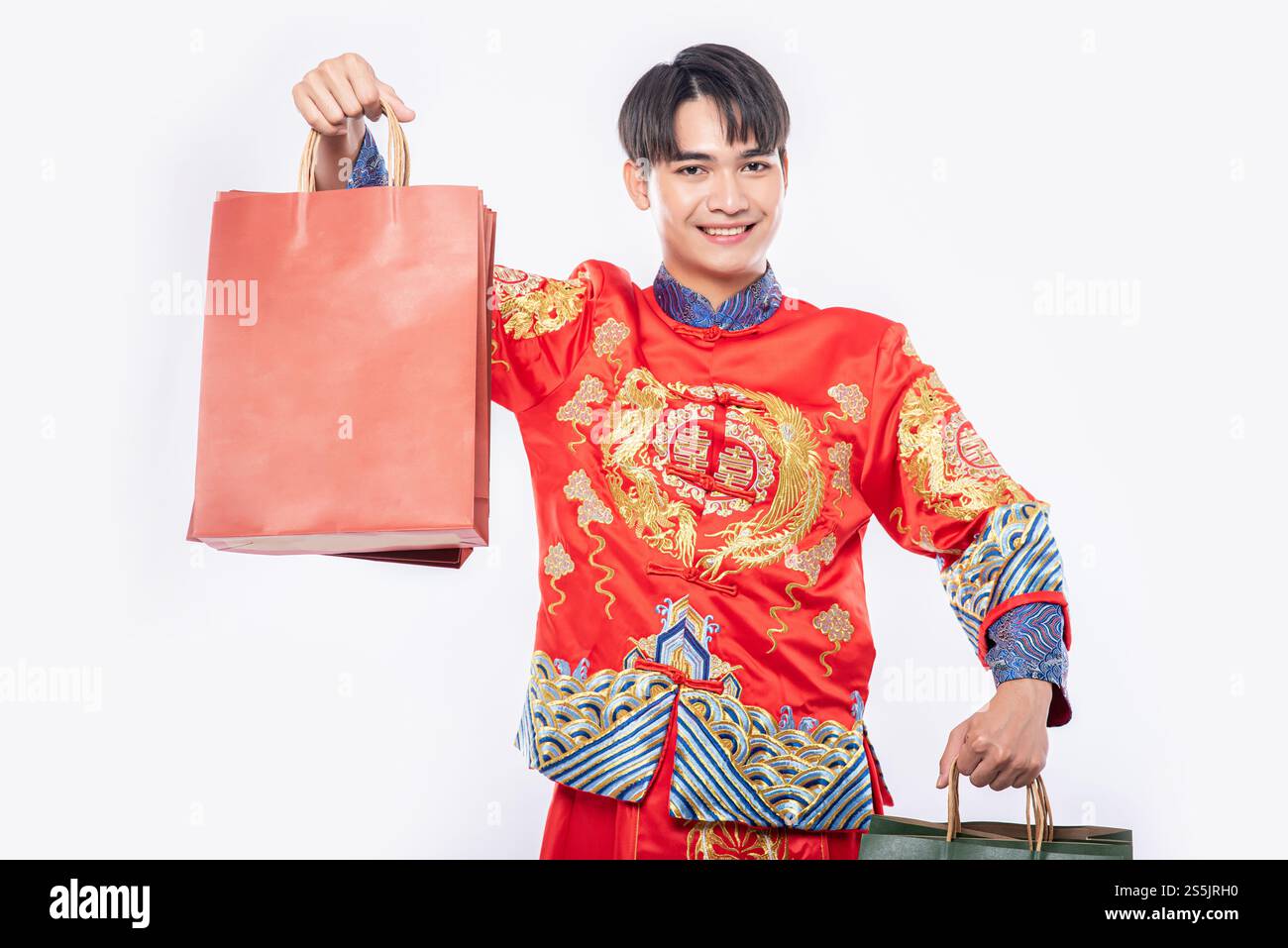 Mann trägt Cheongsam Anzug Lächeln mit Papiertüte vom Einkaufen im chinesischen Neujahr Stockfoto