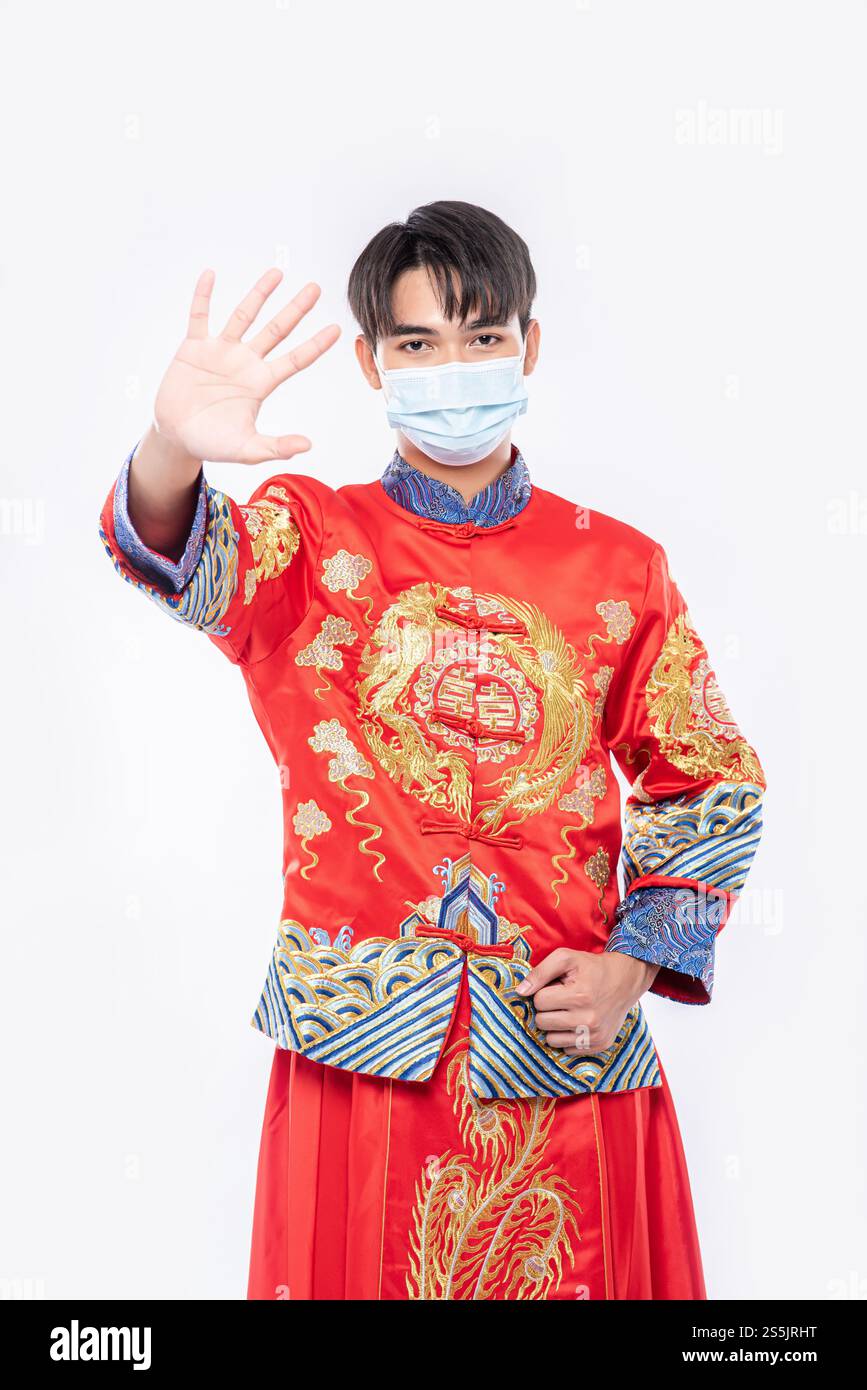 Ein Mann, der einen Cheongsam und eine Maske trägt, zeigt, dass Menschen, die keine Masken tragen, während des Neujahrs nicht einkaufen können. Stockfoto