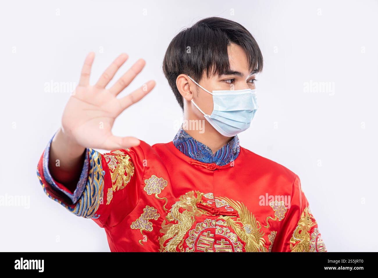 Ein Mann, der einen Cheongsam und eine Maske trägt, zeigt, dass Menschen, die keine Masken tragen, während des Neujahrs nicht einkaufen können. Stockfoto