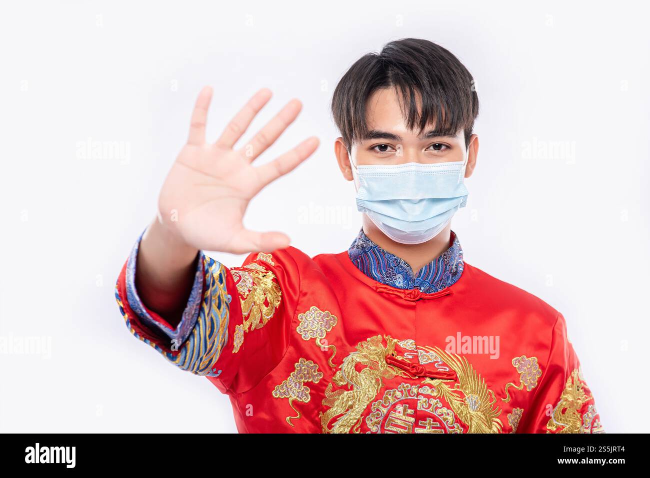 Ein Mann, der einen Cheongsam und eine Maske trägt, zeigt, dass Menschen, die keine Masken tragen, während des Neujahrs nicht einkaufen können. Stockfoto