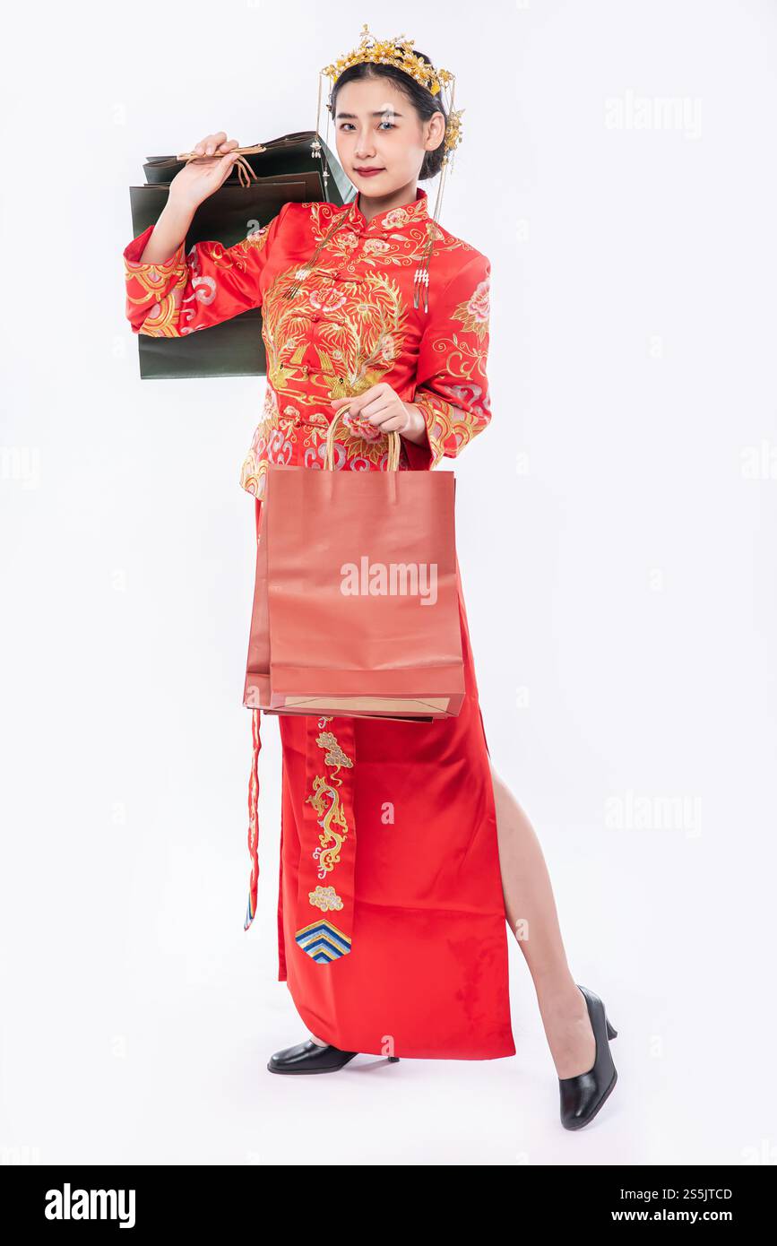 Frau trägt Cheongsam Anzug Lächeln mit Papiertüte vom Einkaufen im chinesischen Neujahr Stockfoto