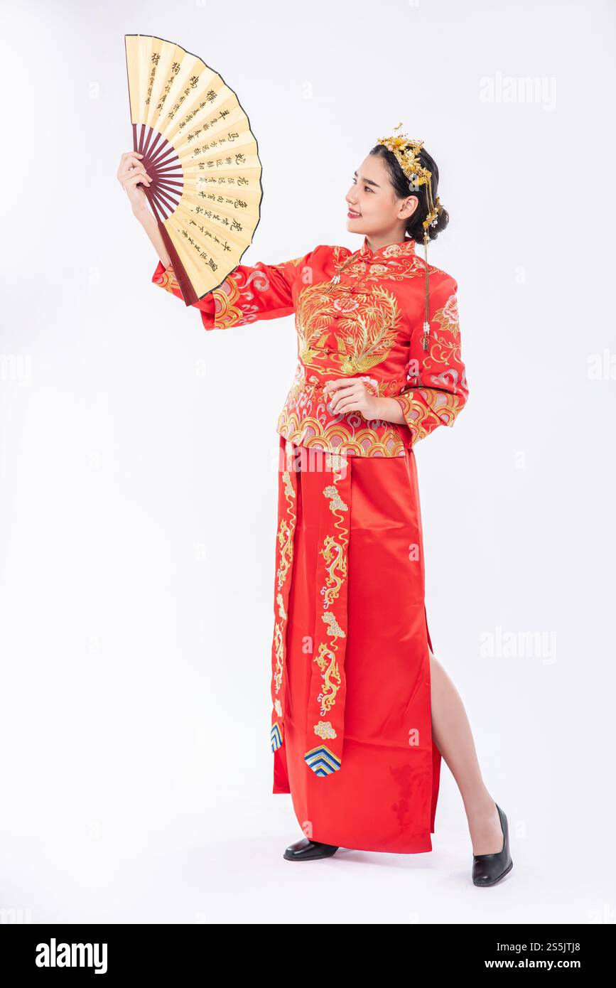 Frau trägt Cheongsam-Anzug zeigt den chinesischen Handfan auf einem großen Event im chinesischen Neujahr Stockfoto