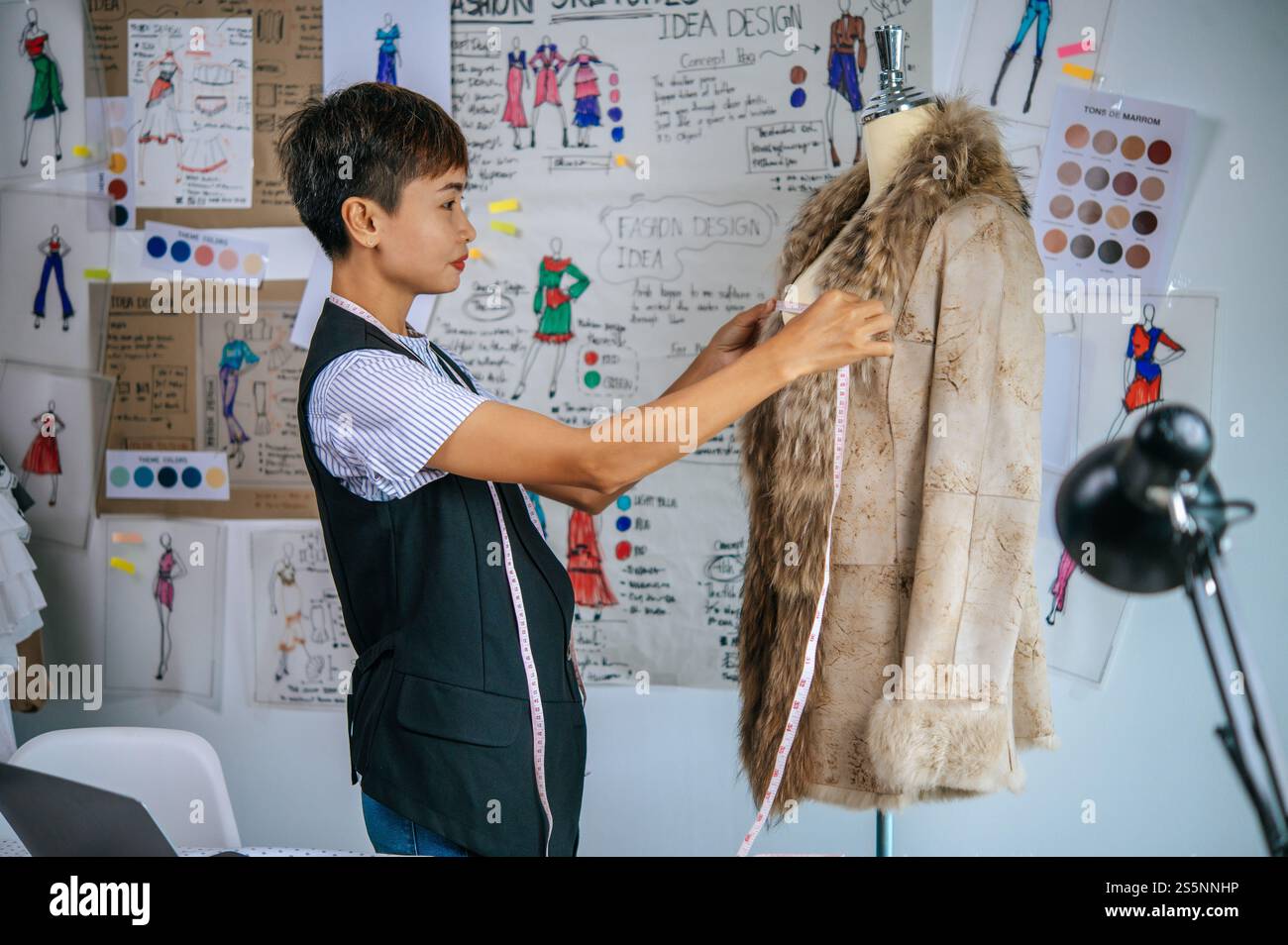 Charmante Schneiderin, die das Maßband an der Schaufensterpuppe benutzt, um das Hemd in der Modedesignwerkstatt zu schneiden Stockfoto