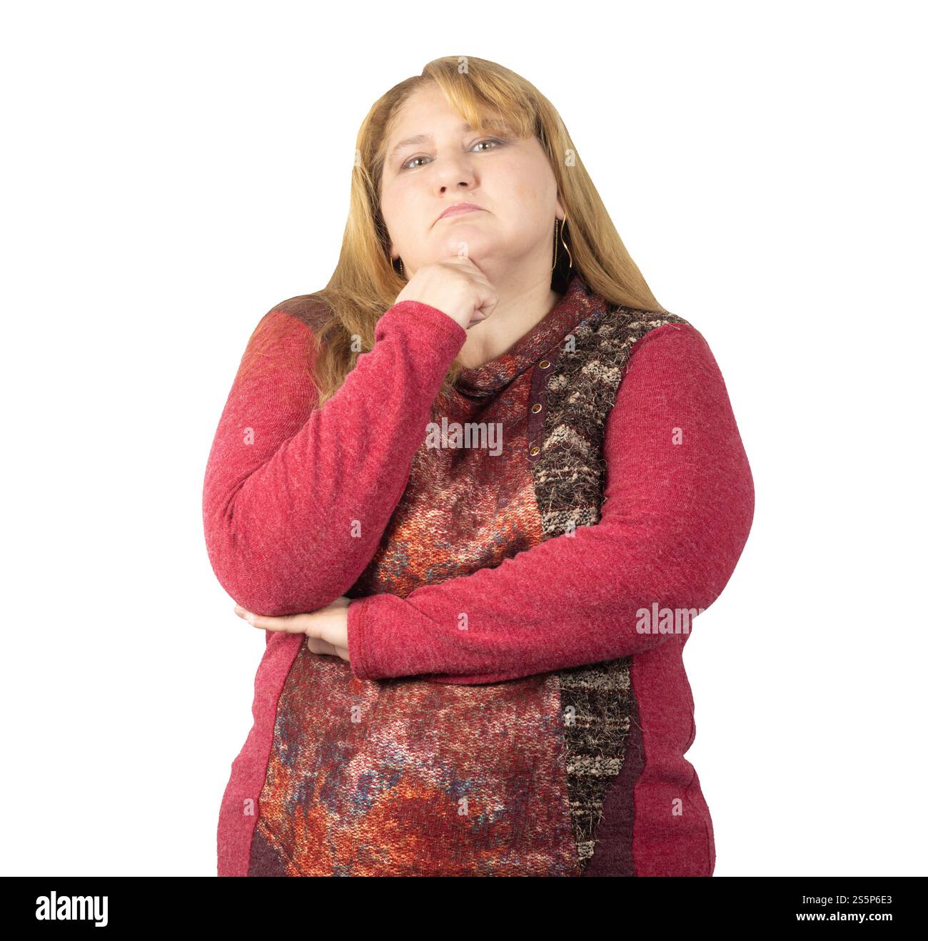 Eine Frau mittleren Alters in einem rot gemusterten Pullover steht mit dem Kinn auf der Hand und einem überkreuzten Arm. Sie strahlt Selbstvertrauen und eine nachdenkliche Demea aus Stockfoto