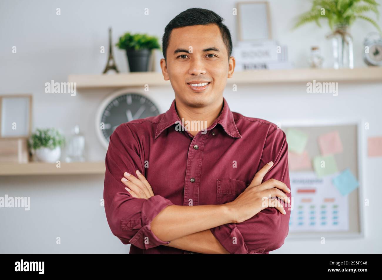 Ein männlicher Arbeiter beendet seinen Job und faltet die Arme und lächelt. Stockfoto