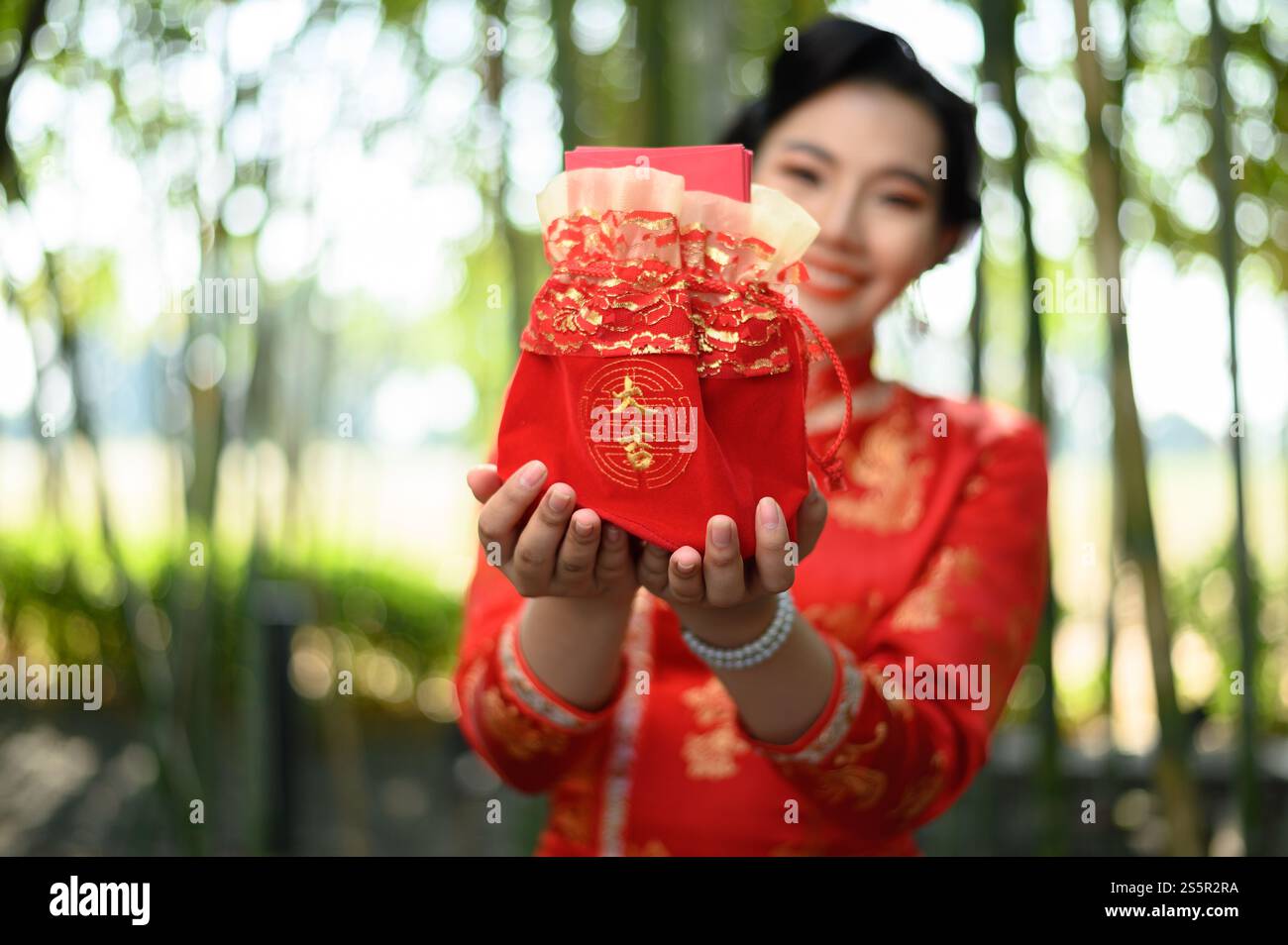 Selektive Fokusumschläge in roter Amuletttasche mit chinesischem Alphabet bedeuten Glück und Glück auf den Händen einer hübschen Frau in chinesischer Kleidung Stockfoto