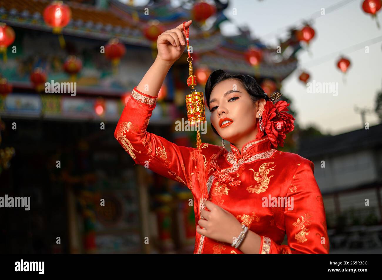 Porträt Asiatische schöne Frau, die einen Cheongsam trägt, lächelt und china-Amulett hält, posiert am Schrein am chinesischen Neujahrsfest, Kopierraum Stockfoto