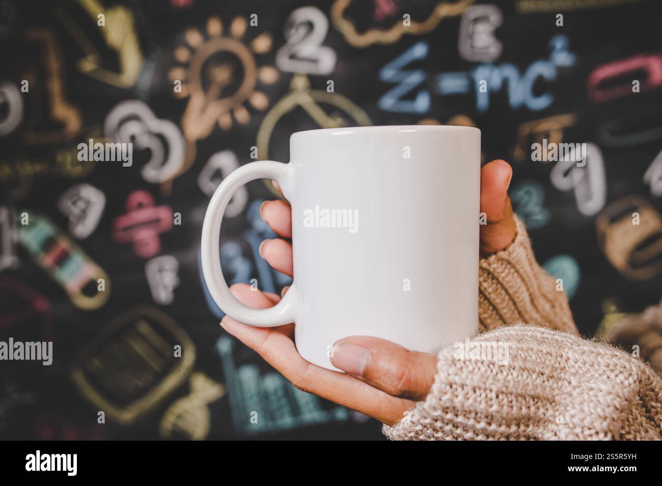 Hand hält den Becher im Klassenzimmer. Stockfoto