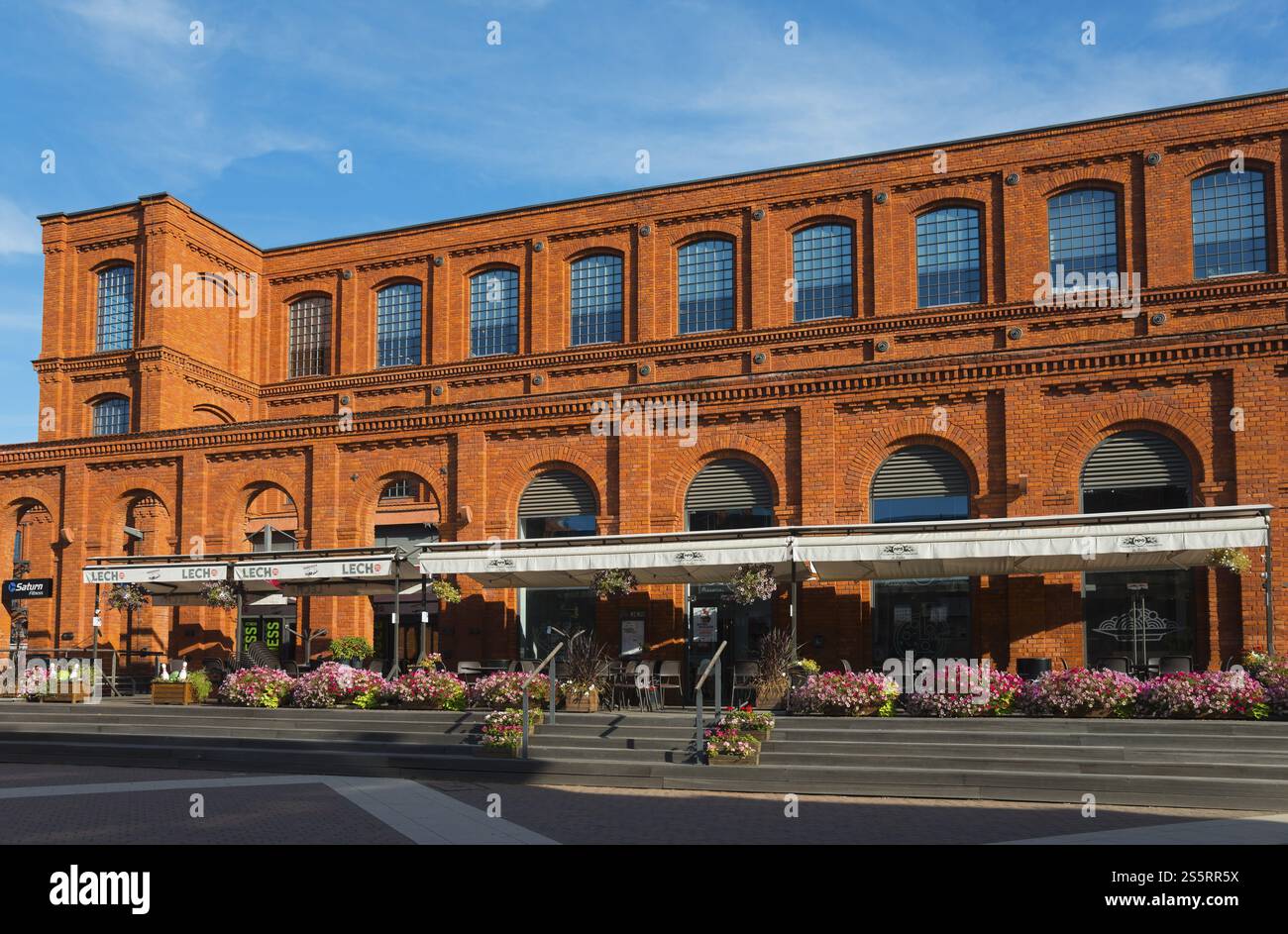 Sonnendurchflutetes Backsteingebäude mit Blumen vor blauem Himmel, Manufaktura, Lodz, Lodz, Lodz, Polen, Manufaktura, Lodz, Lodz, Lodz, Polen, Europa Stockfoto