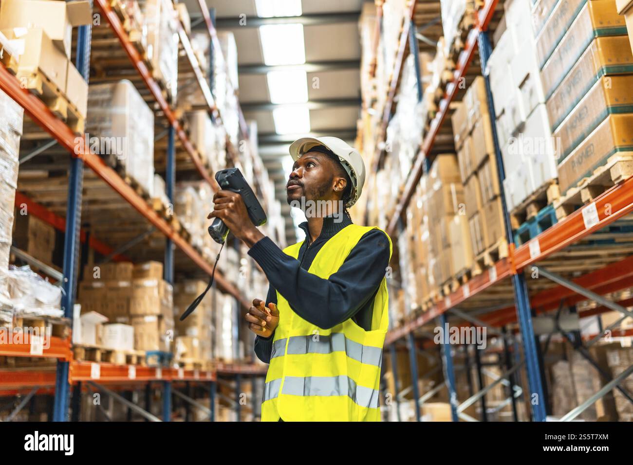 Afrikanischer Mann mit Scanner, um die Barcodes zu lesen und die Pakete in einem Lager zu überprüfen Stockfoto