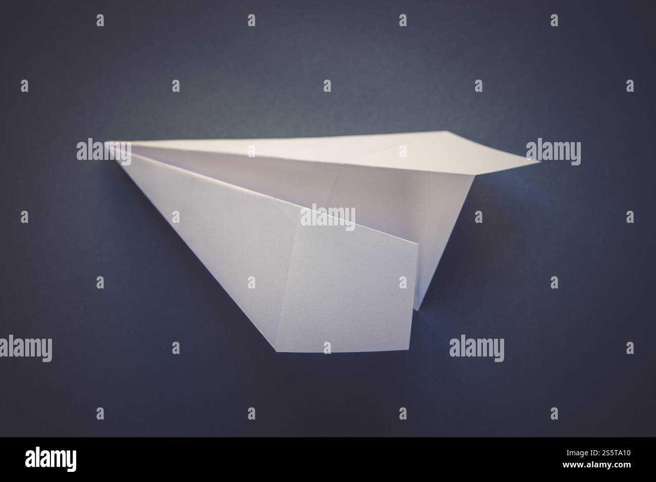 Weißes Papierflugzeug Origami isoliert auf einem leeren grauen Hintergrund. Weißes Papierflugzeug Origami isoliert auf grauem Hintergrund Stockfoto