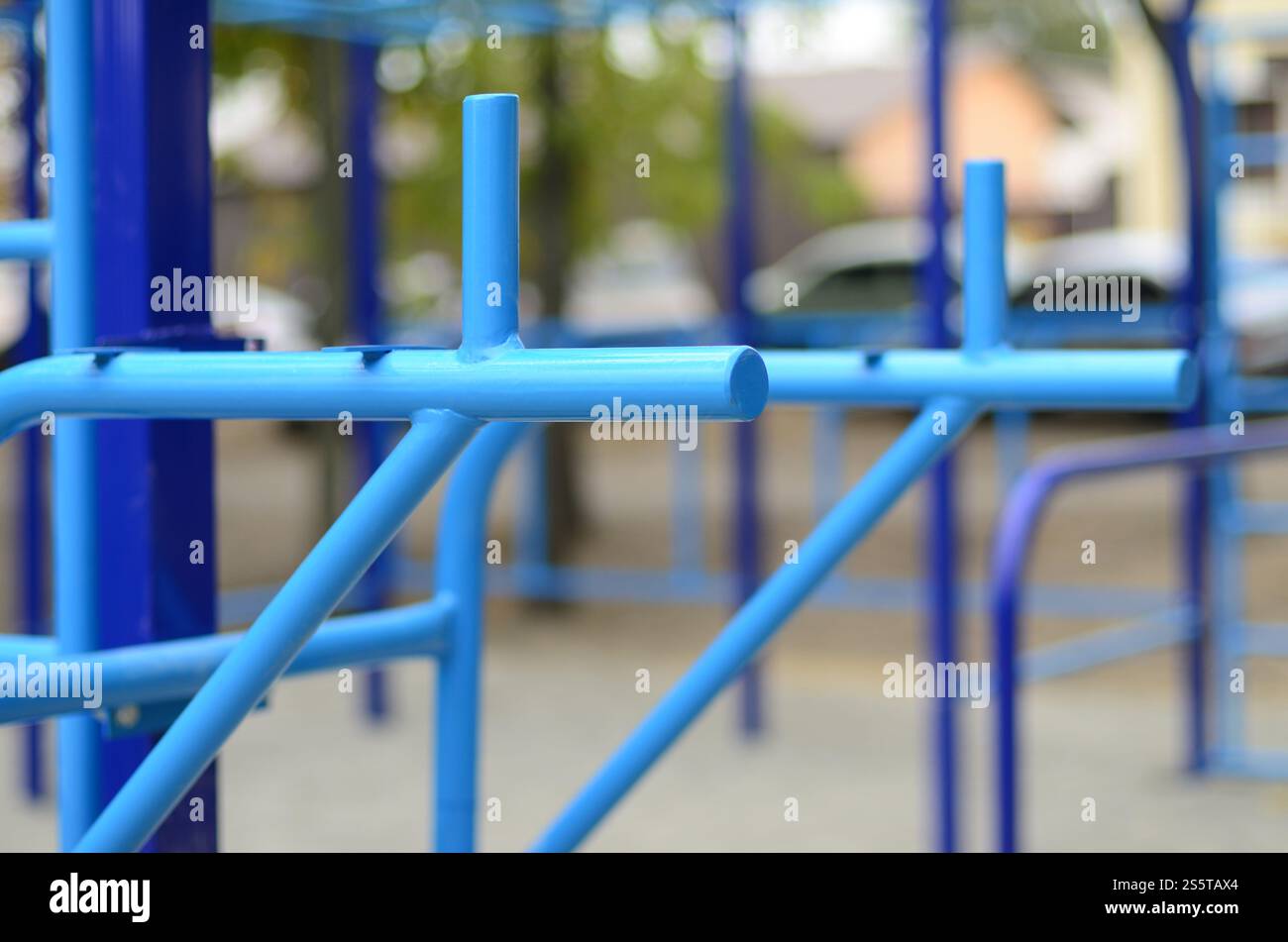 Blaue Metallrohre und Querstangen vor einem Straßensportplatz für Leichtathletik-Training. Sportgeräte im Freien. Makrofoto mit selektiv Stockfoto