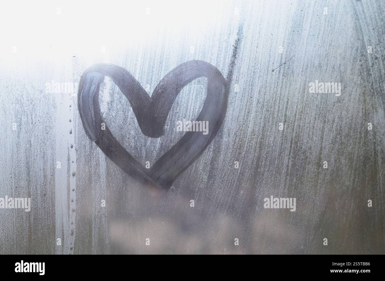 Eine herzförmige Zeichnung durch einen Finger auf einen Beschlagenen Glas im regnerischen Wetter gezeichnet Stockfoto