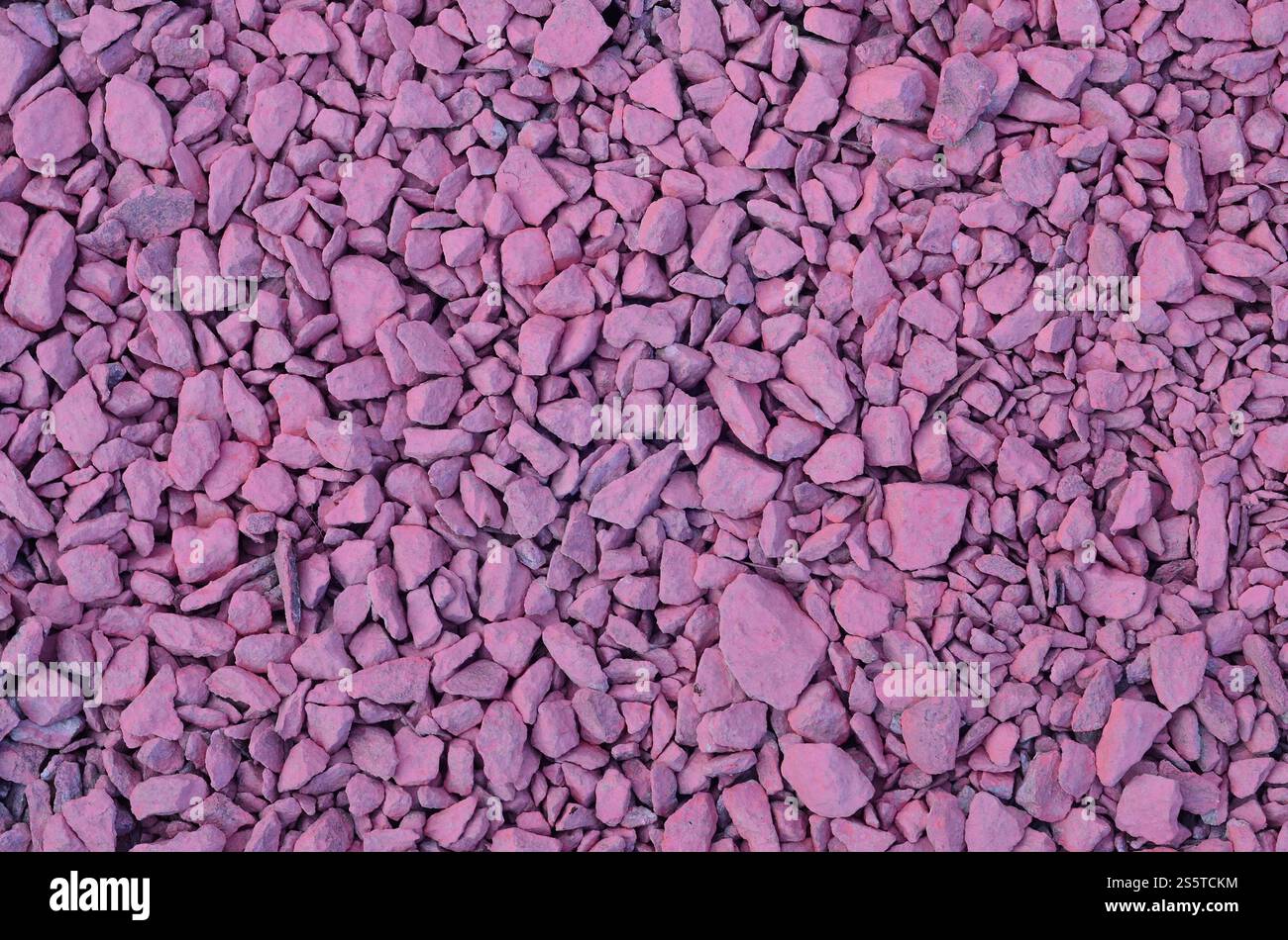 Textur aus einem Haufen zerquetschtem Stein, in hellrosa Farbe gemalt. Hintergrundbild vieler rosafarbener Steine unterschiedlicher Formen und Größen. Textur eines Stockfoto