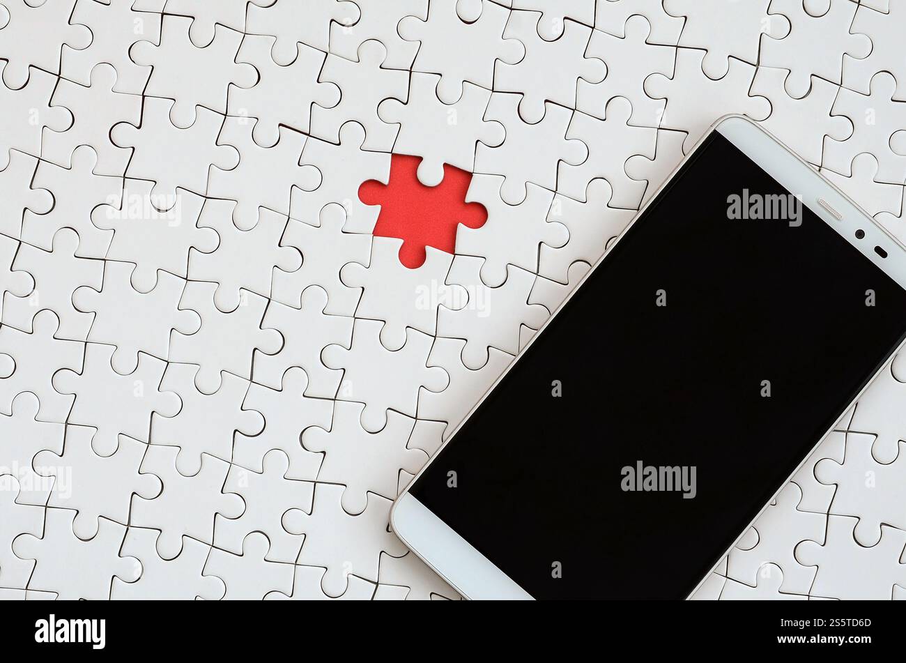 Ein modernes, großes Smartphone mit Touchscreen liegt in einem weißen Puzzle in zusammengebautem Zustand Stockfoto