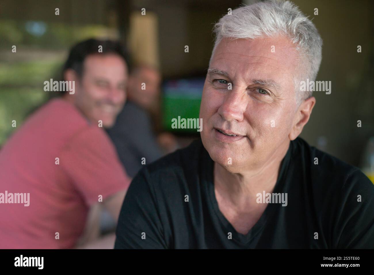 Glücklicher reifer Mann, der Zeit mit Freunden genießt, Sportspiele im Fernsehen ansieht, sich auf den Vordergrund konzentriert Stockfoto