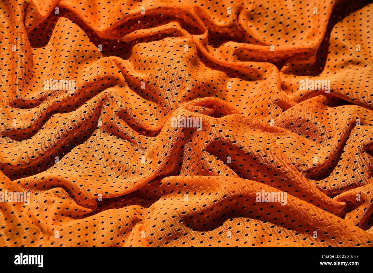 Sport Bekleidung Stoff Textur Hintergrund. Blick von oben auf die orange Polyester nylon Tuch textile Oberfläche. Farbige Basketball Shirt mit Freiraum für Text Stockfoto
