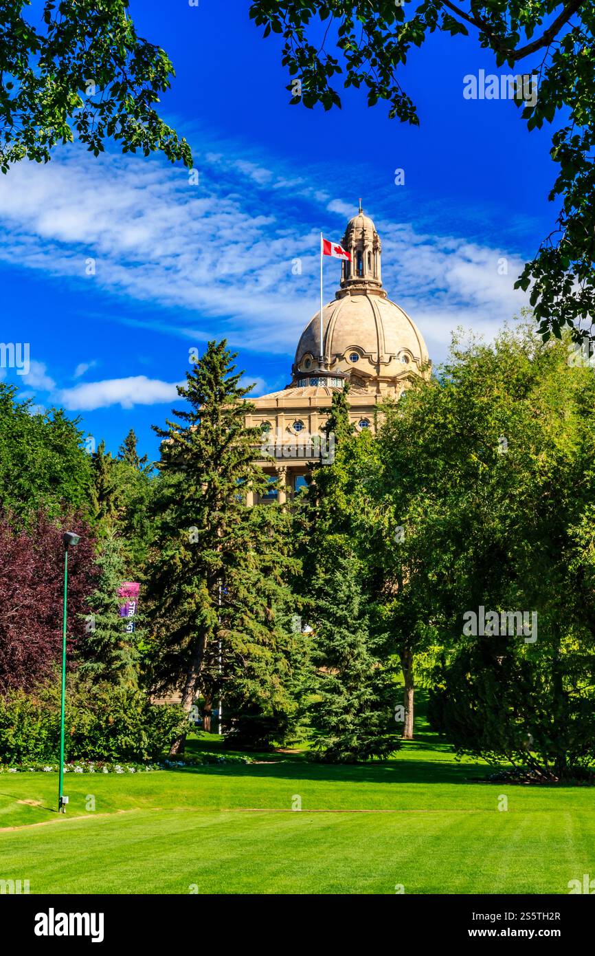 Ein großes Gebäude mit einer Flagge darüber. Der Himmel ist blau und es gibt Bäume im Hintergrund Stockfoto