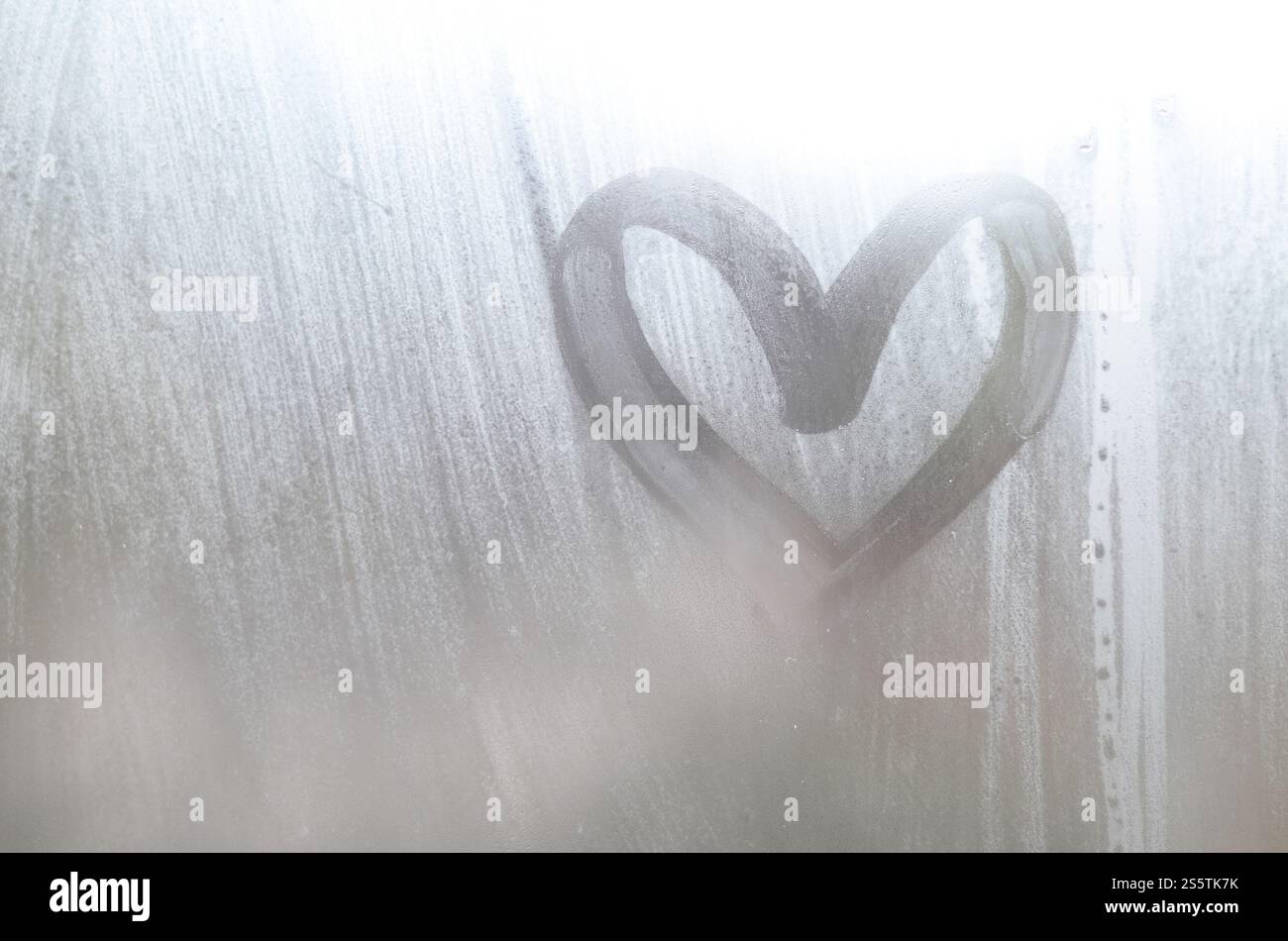 Eine herzförmige Zeichnung durch einen Finger auf einen Beschlagenen Glas im regnerischen Wetter gezeichnet Stockfoto