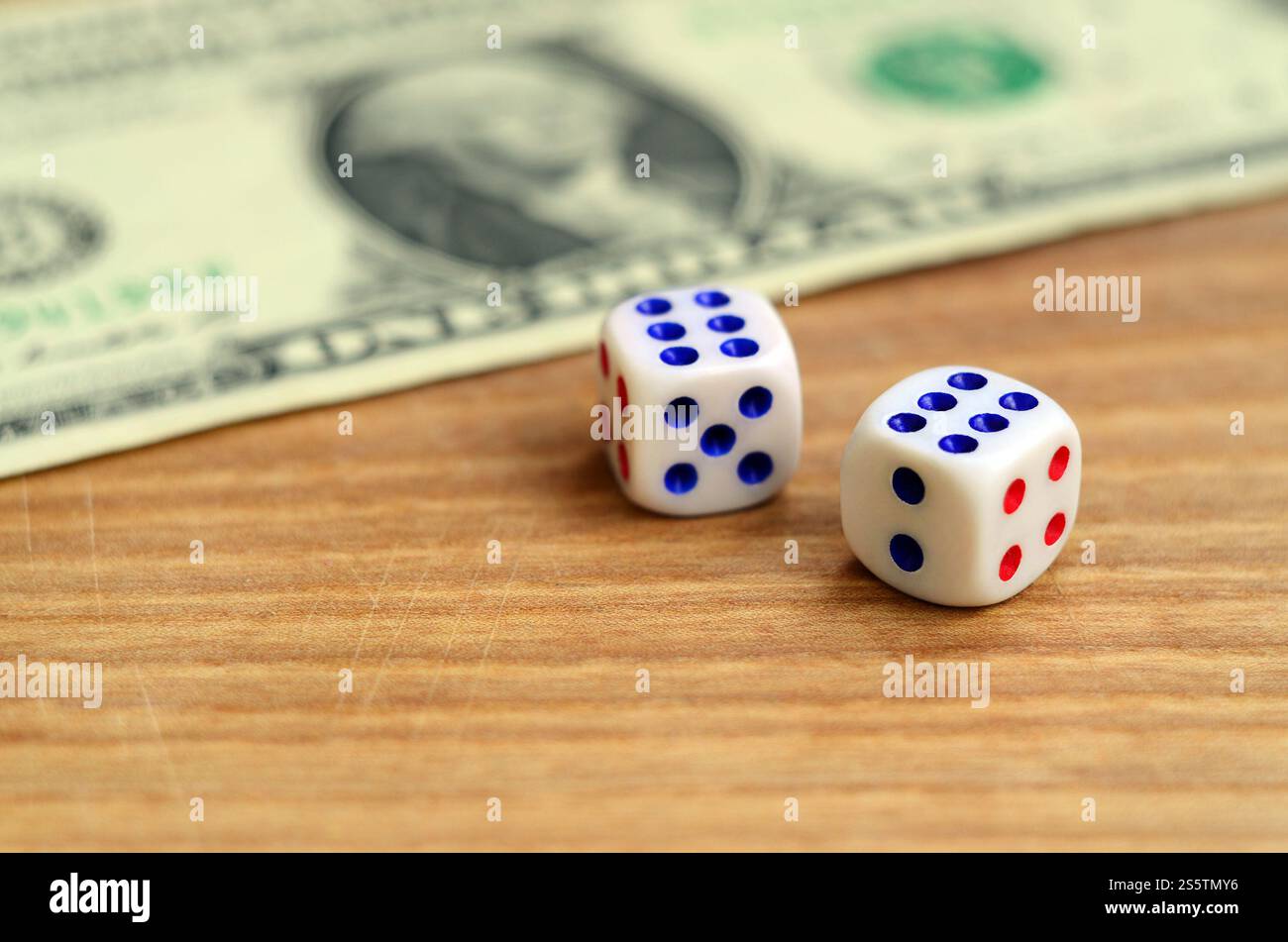 Weiße Würfel sind neben einem dollarschein von US-Dollar auf einem hölzernen Hintergrund. Das Konzept des Glücksspiels mit Preisen in monetären Einheiten Stockfoto