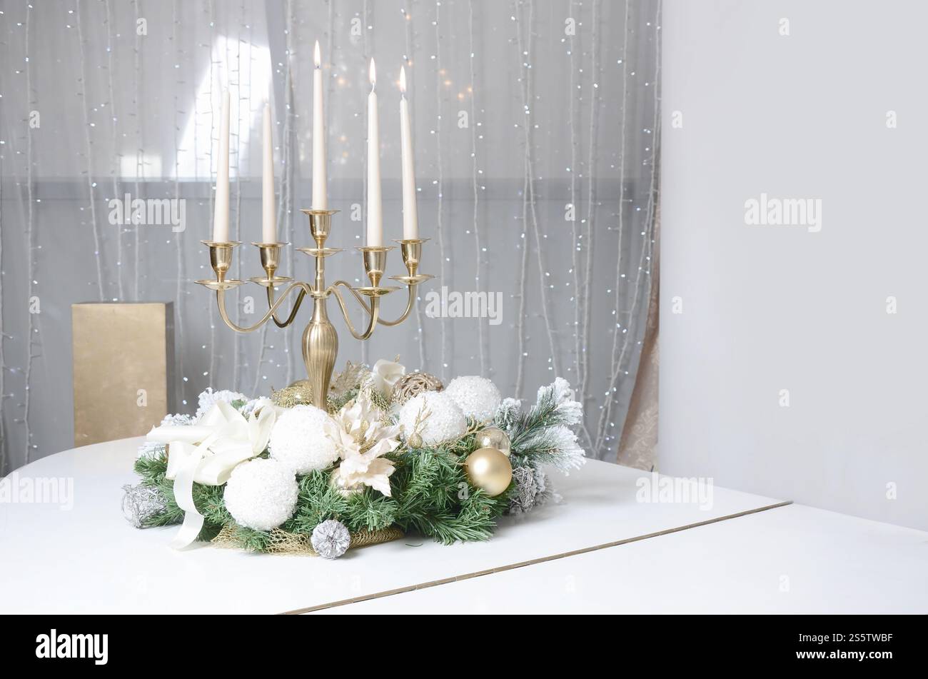 Neujahrsdekorationen und ein goldener Kerzenleuchter mit brennenden Kerzen stehen auf der Oberfläche eines weißen Flügels Stockfoto